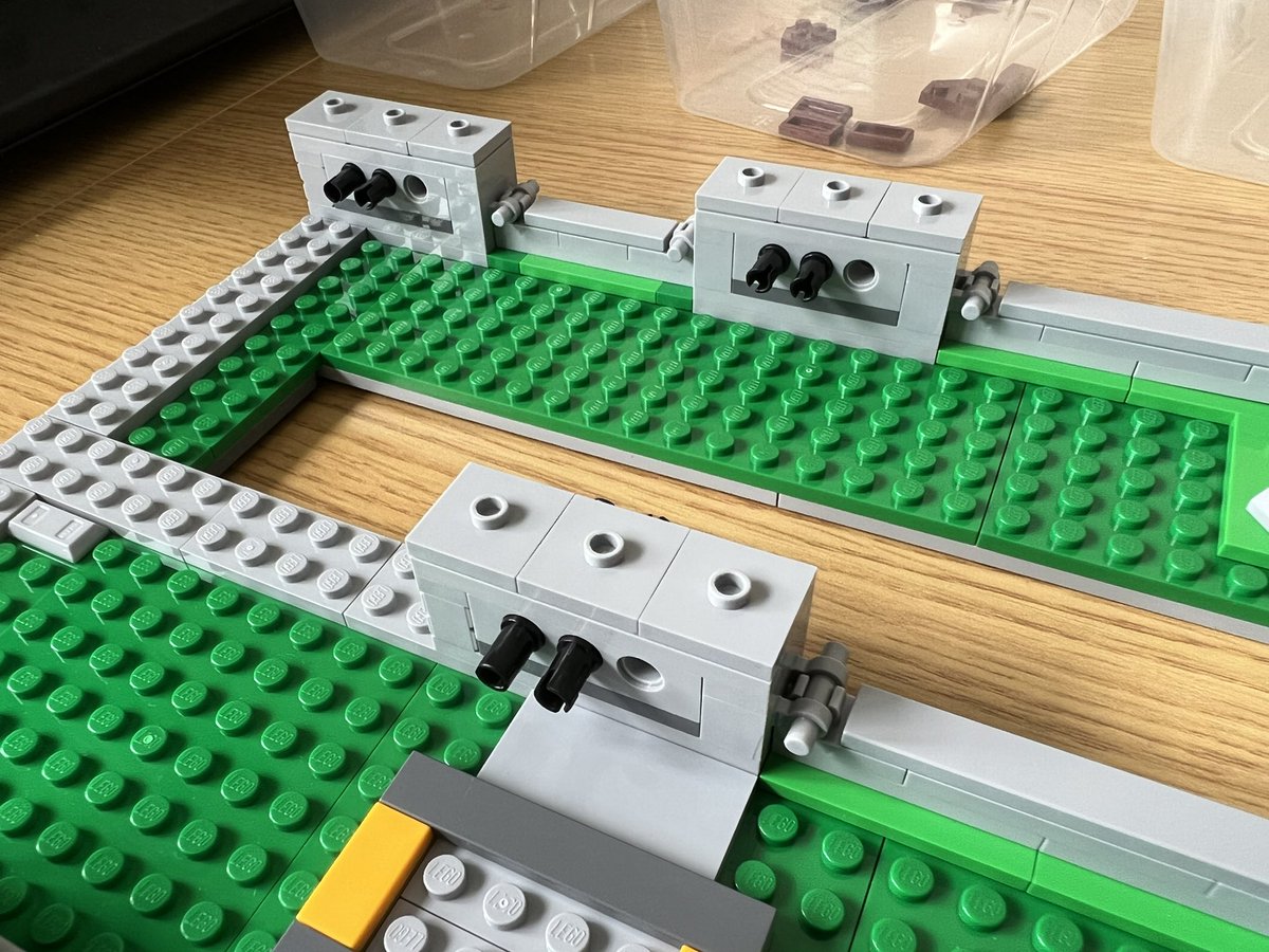 A closeup of three lego structures that are grey rectangles with black pins sticking out the front