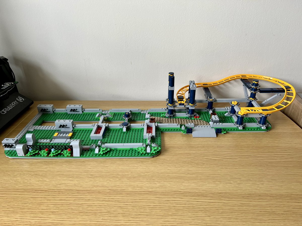 A partially built lego roller coaster. On the right hand side is a small curve of yellow track that’s not connected to anything. The rest of the build is mainly grey railings in a grid layout.