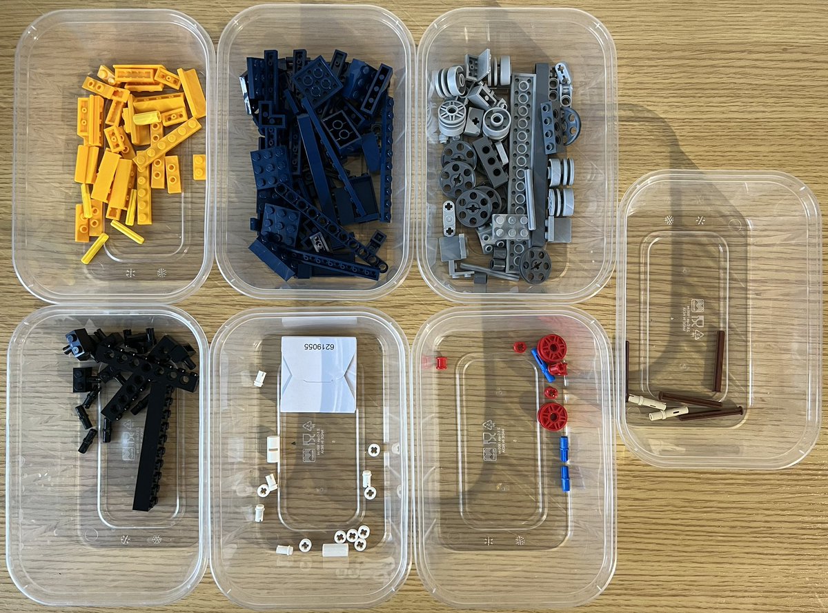 Seven tubs of lego sorted by colour. There are lots of grey wheels, and a small square cardboard box that only says “6219055”.